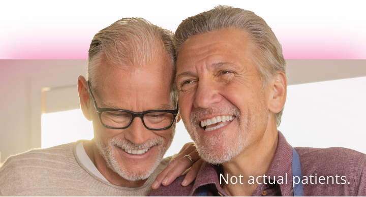 Visual of virologically suppressed middle-aged male couple, laughing and looking reassuringly at each other in a park setting 